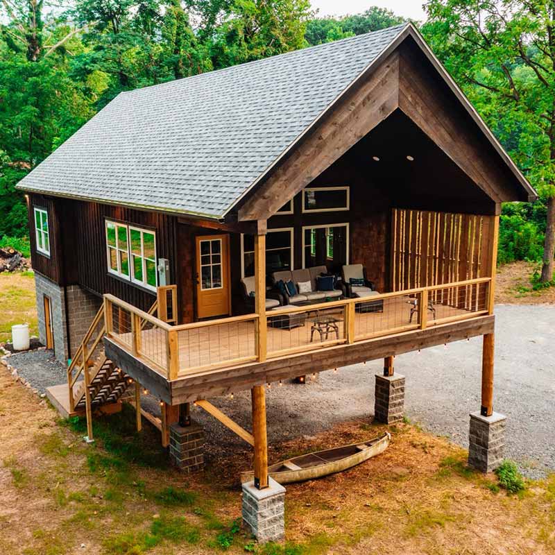 Rustic cabin raised on stilts with large porch overlooking the Black Fork of the Cheat River.