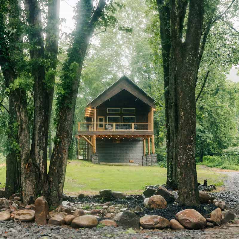 Cabin and back yard framed by trees and landscaping.